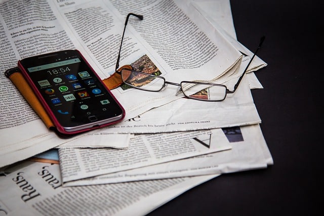 Newspapers, glasses and mobile phone