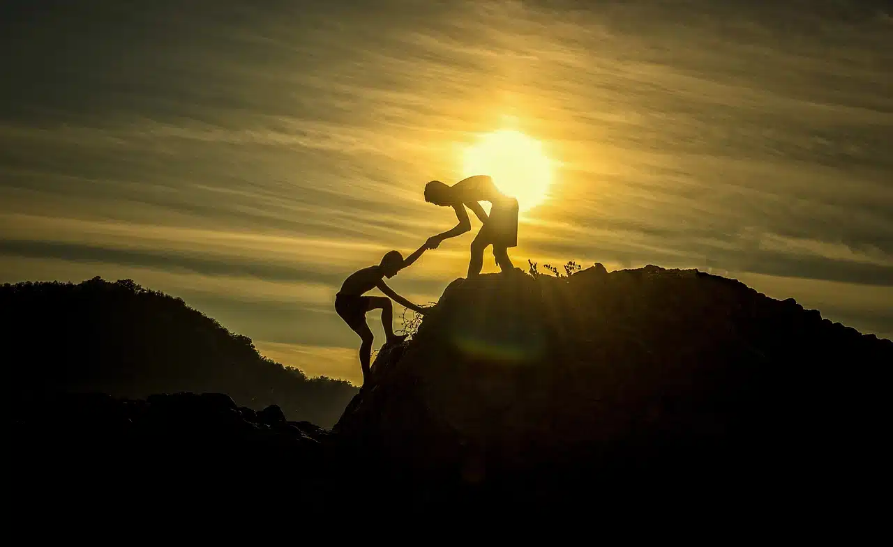 Person helping another person climb a mountain