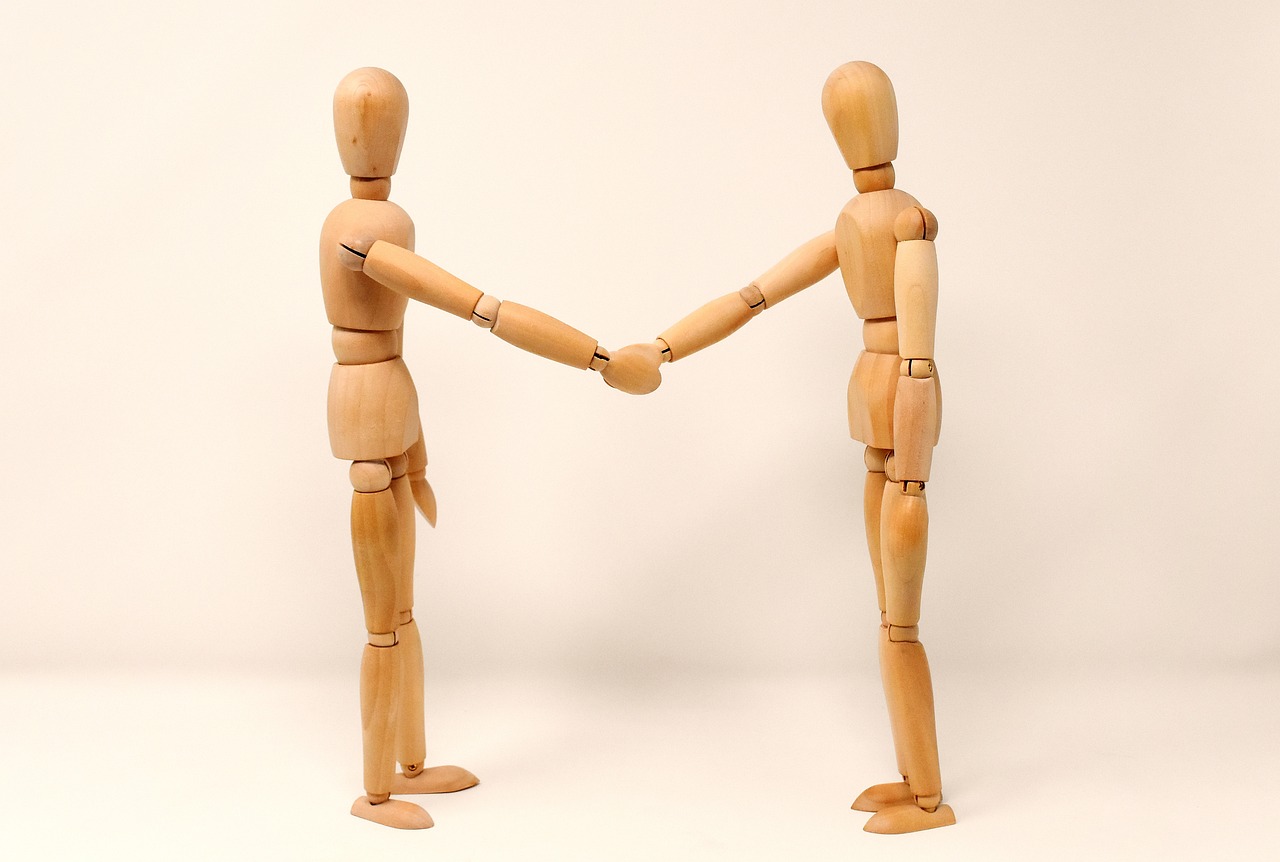 Wooden dolls shaking hands