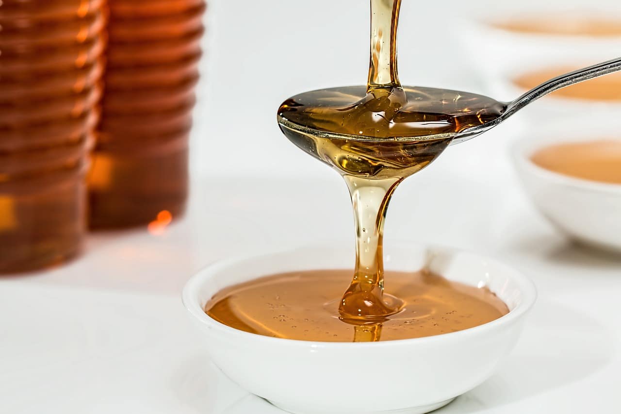 Honey poured over a spoon and a bowl