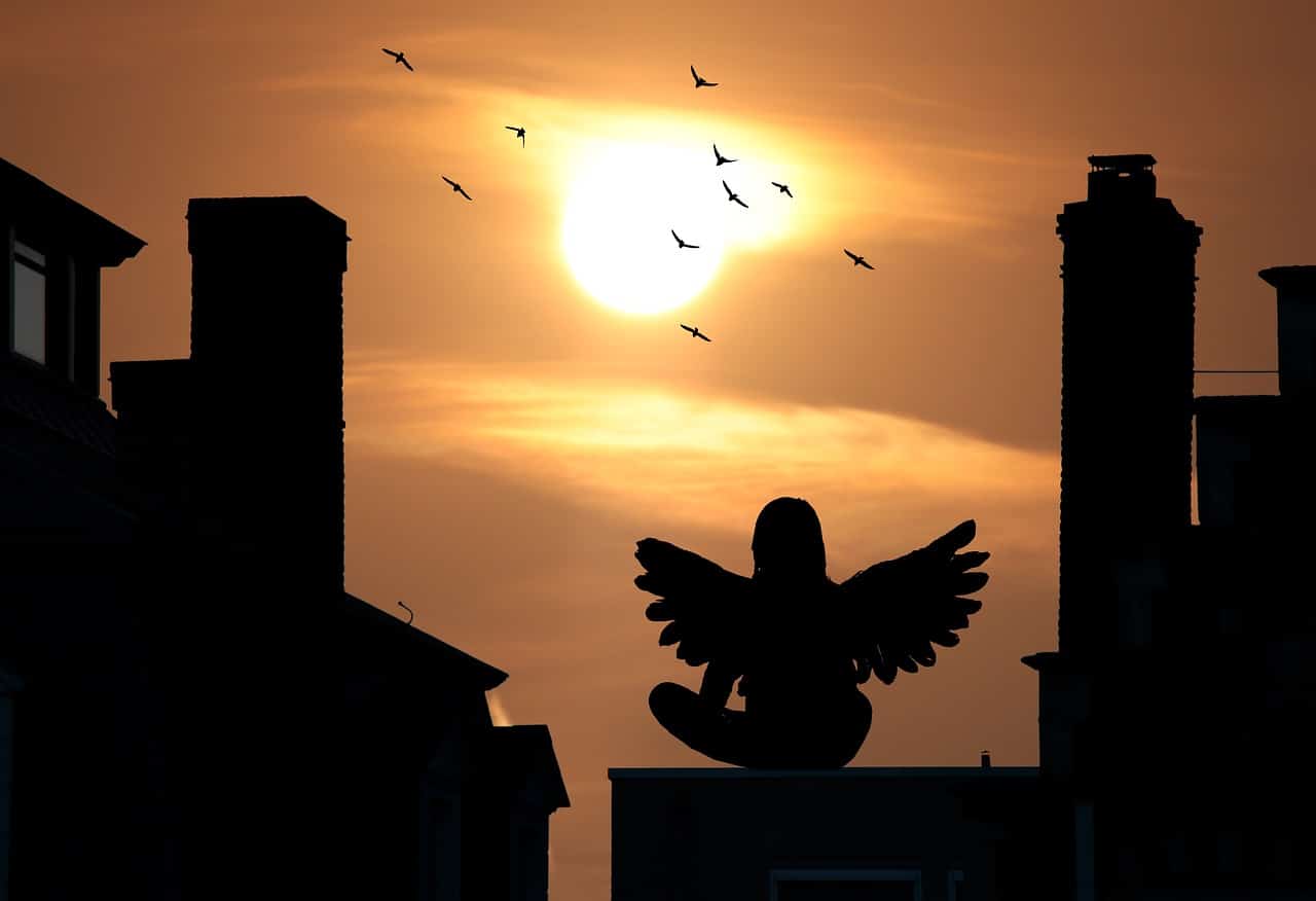 An angel on a rooftop at sunset