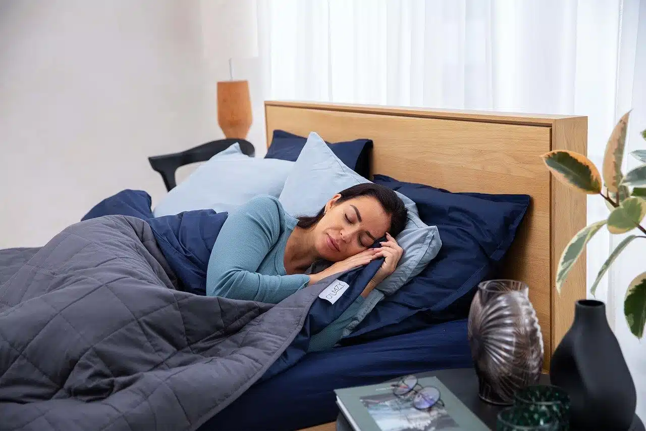 Woman sleeping in bed with gray duvet and blue sheets