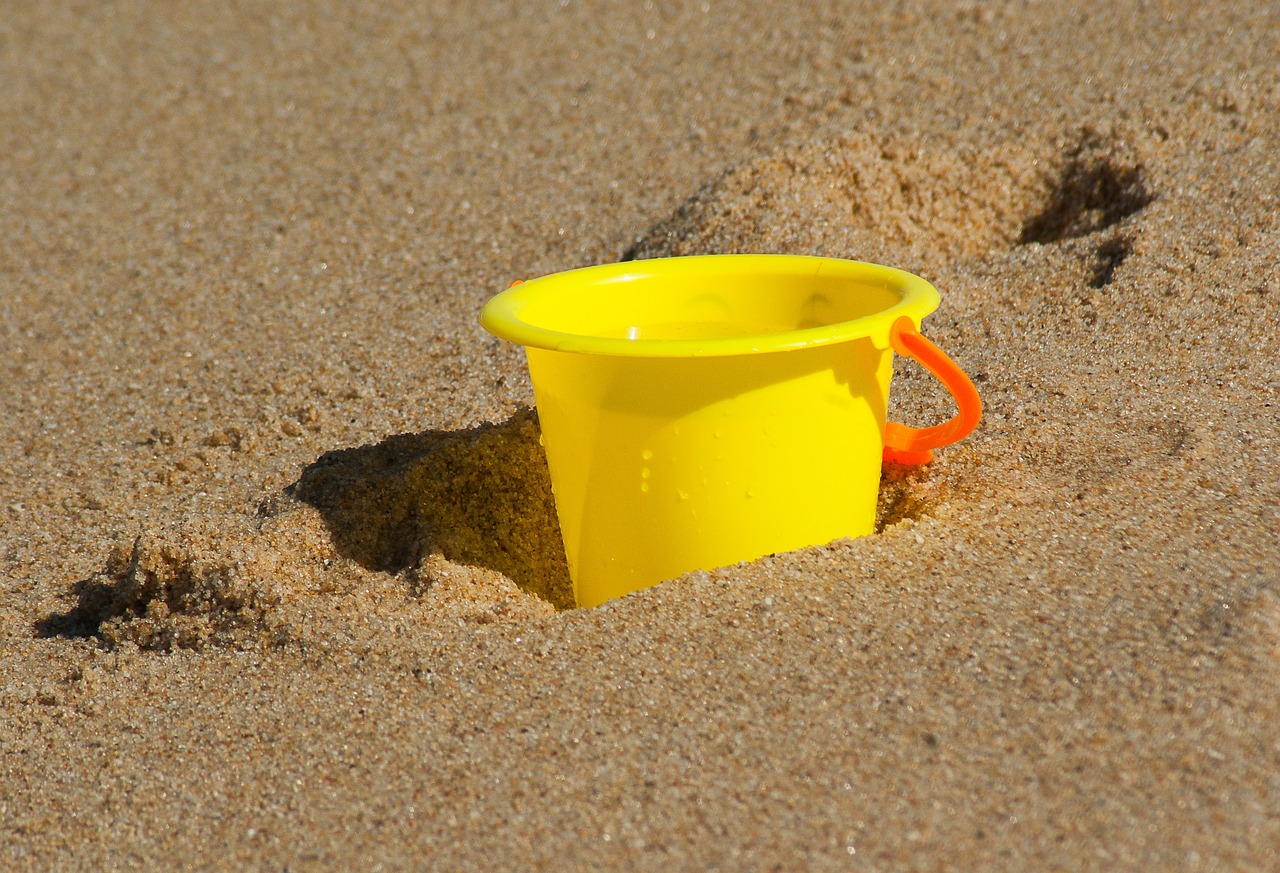 Yellow beach bucket on sand