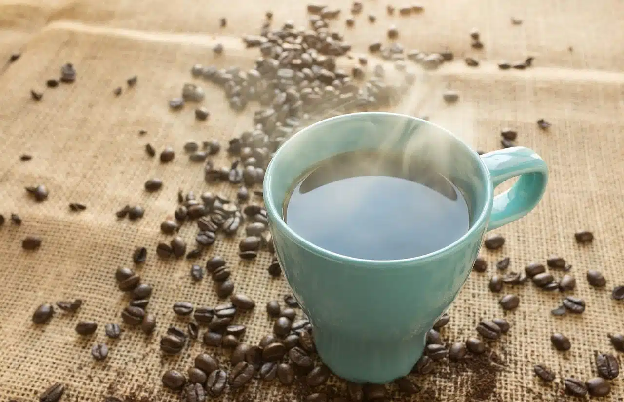 A cup of hot coffee with beans around