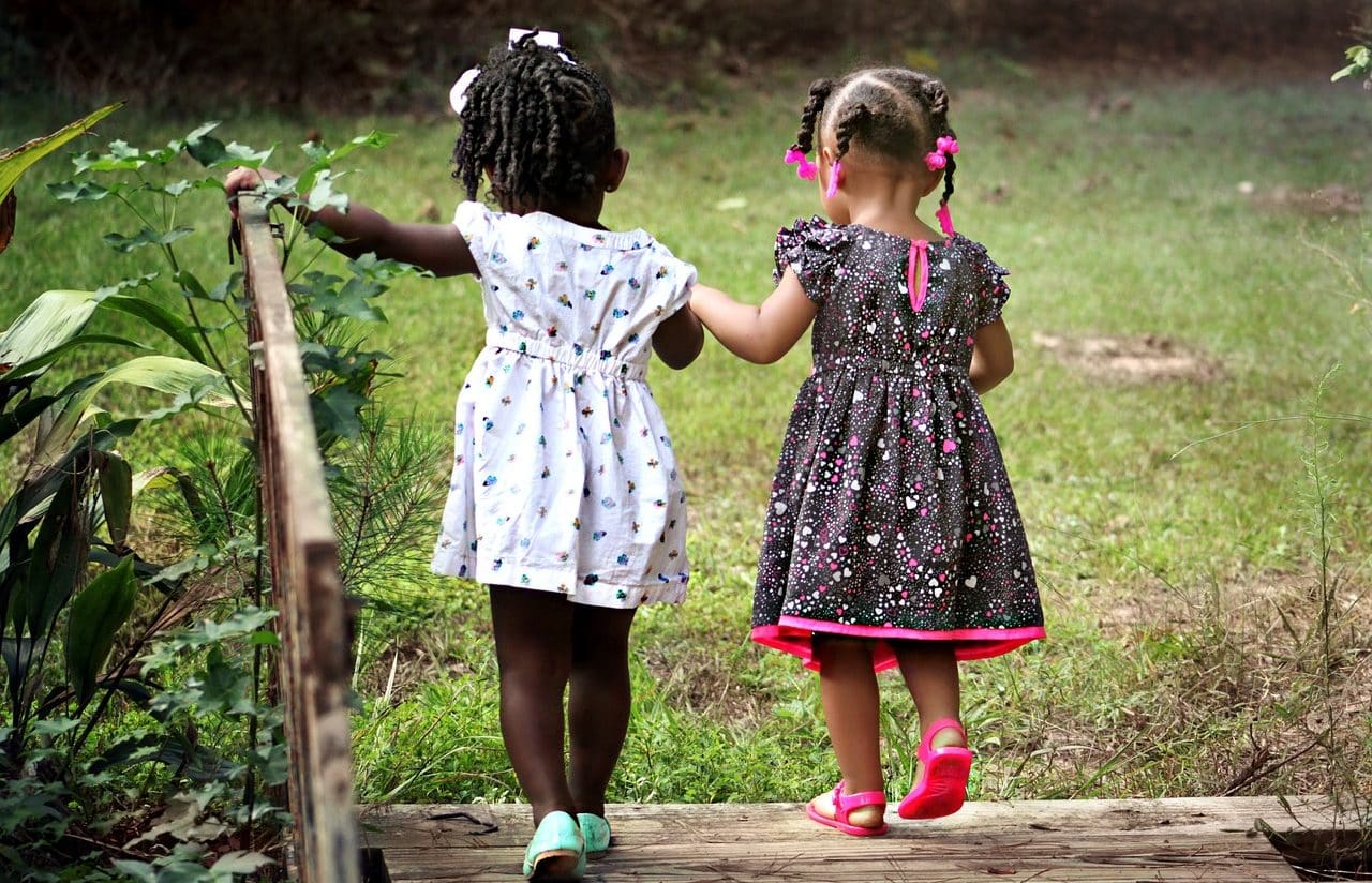 Two girls crossing a bridge in the countryside