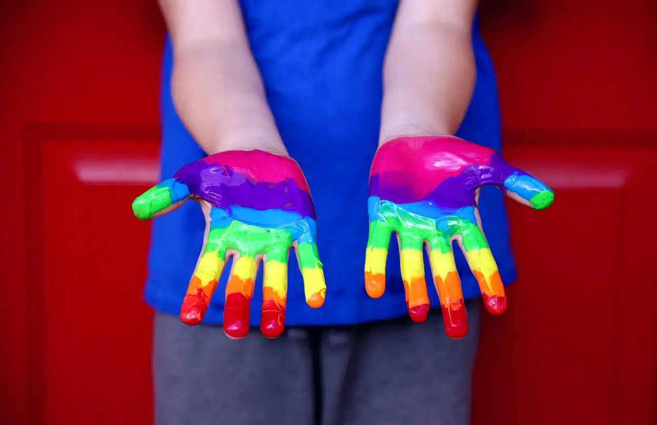 Person with hands painted with rainbow colors