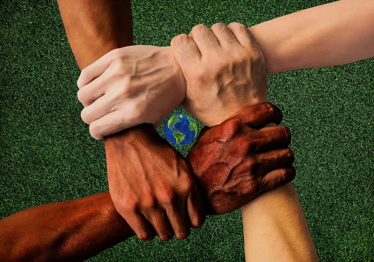 Four people of different races holding arms