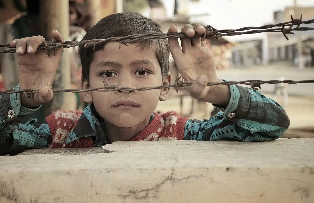 Poor child behind wire fence