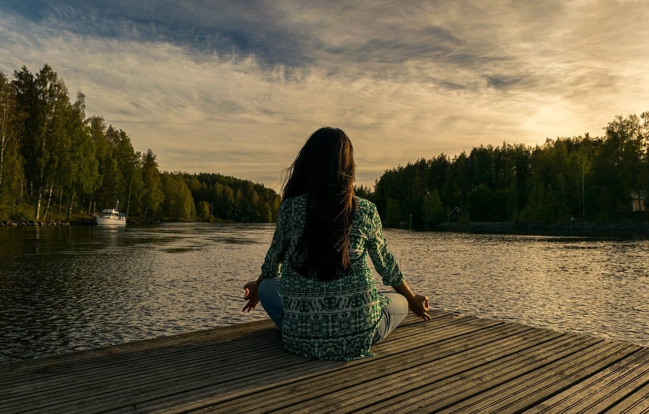 Woman meditating next to a lake