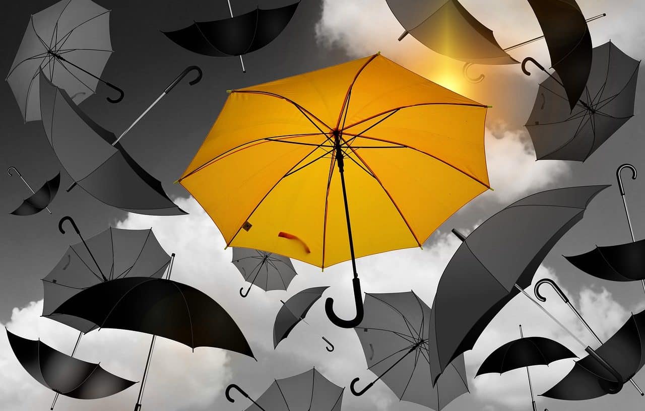 Yellow umbrella among many gray ones