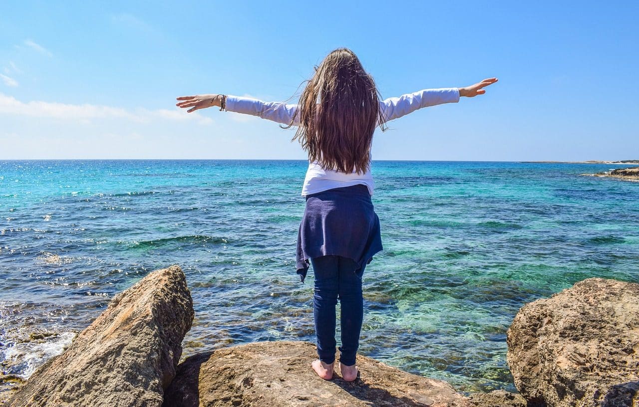 Woman with arms outstretched in front of the sea