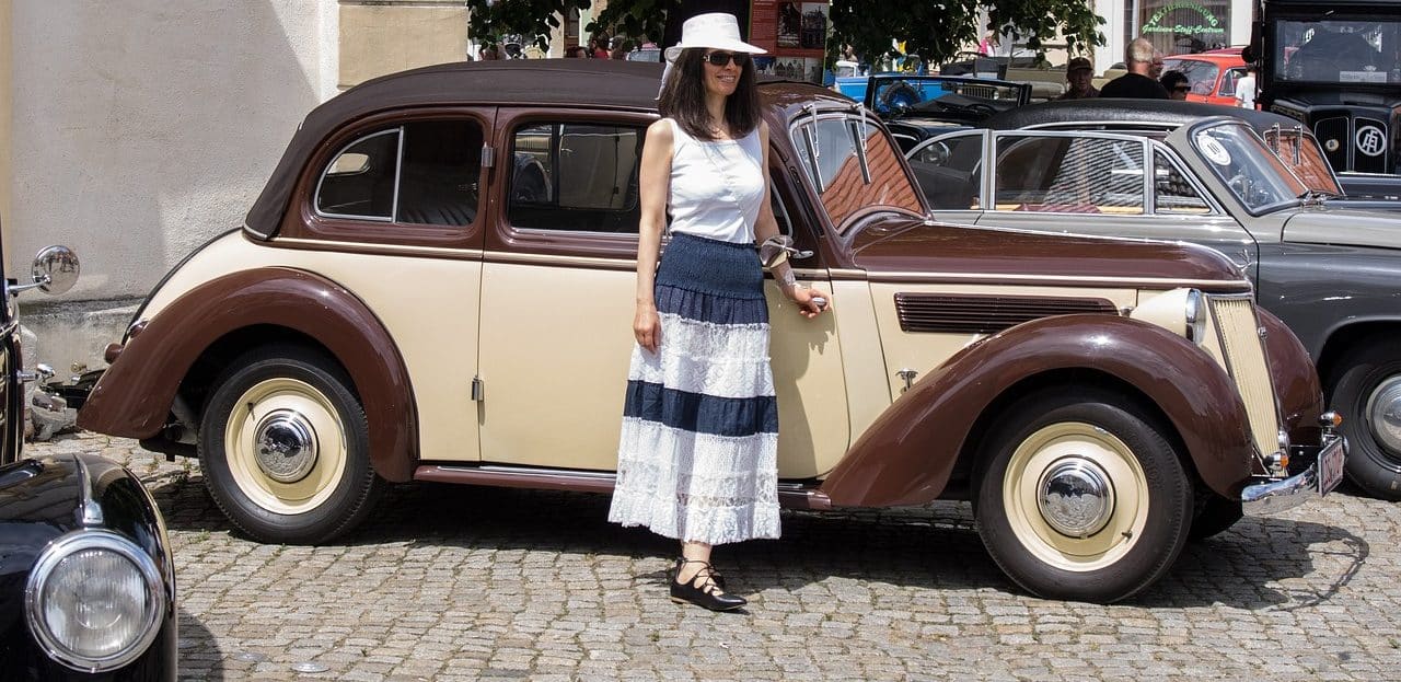 Woman standing next to a brown vintage car