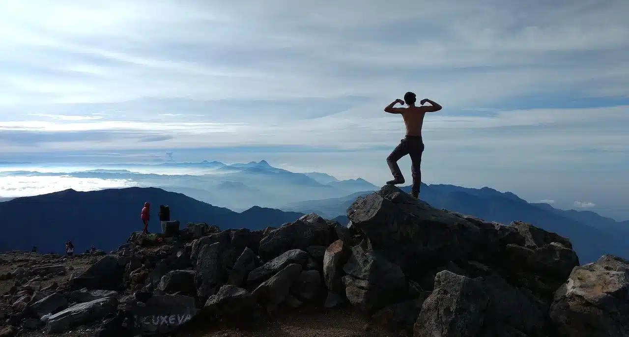 Man marking his muscles on the top of a mountain