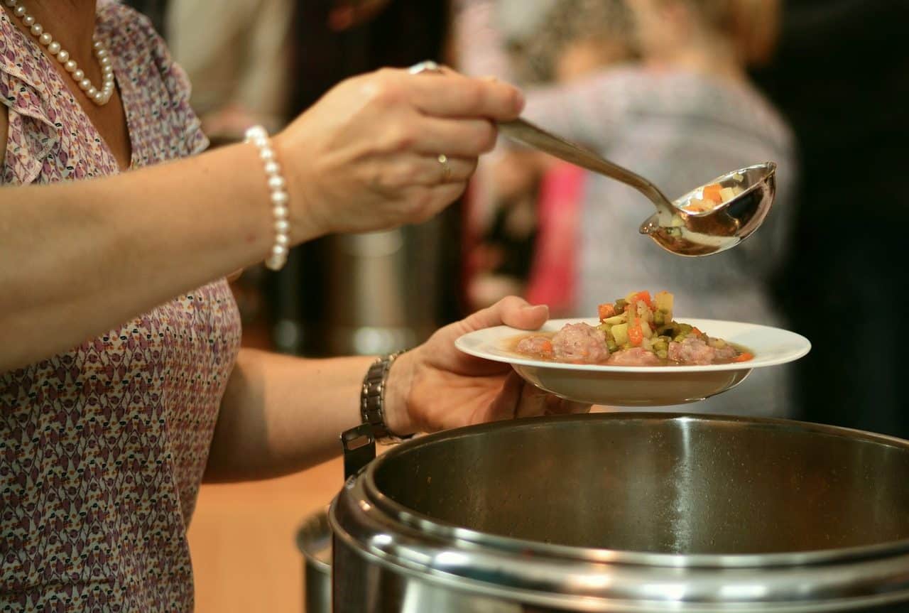 Woman serving a plate of food in a community kitchen