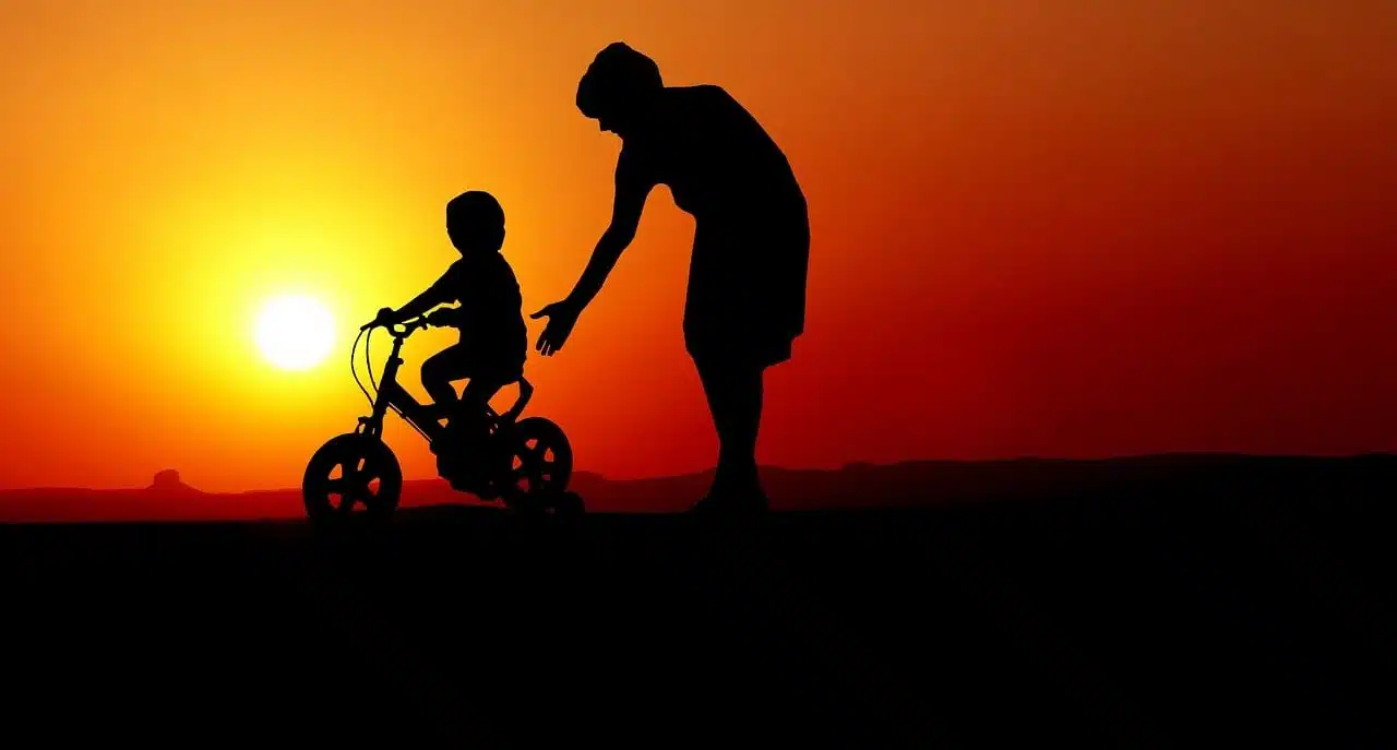 Boy learning to ride a bicycle with an adult