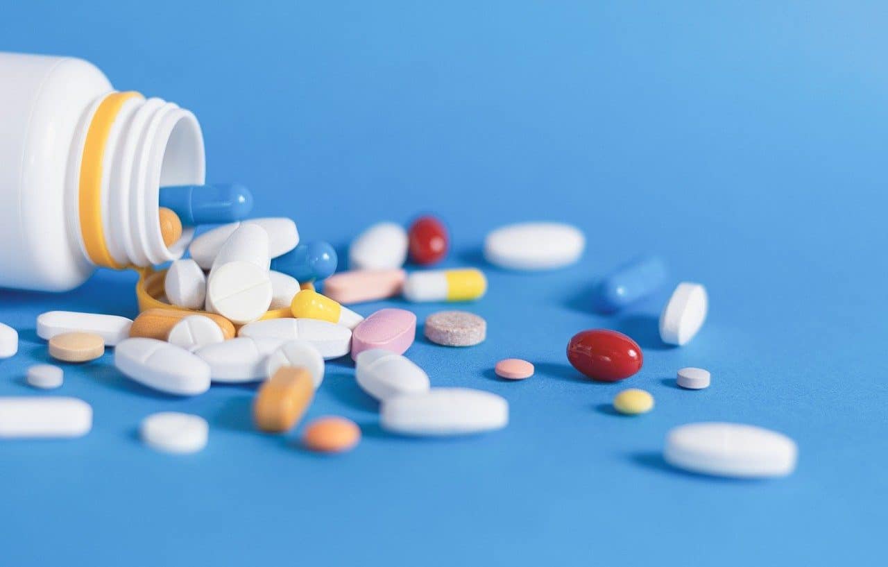 Bottle with various tablets spilled on a table