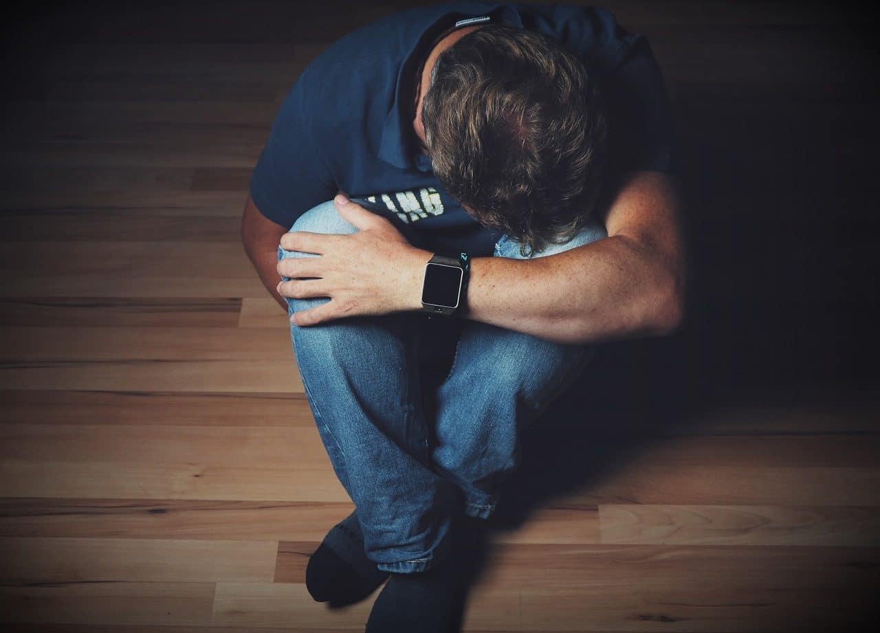 Man sitting on the floor with his head on his knees