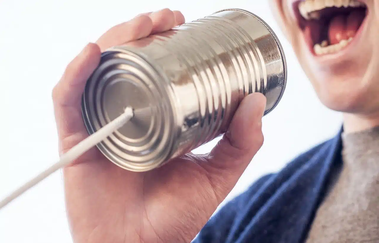 Boy talking through a can attached with a rope to another.