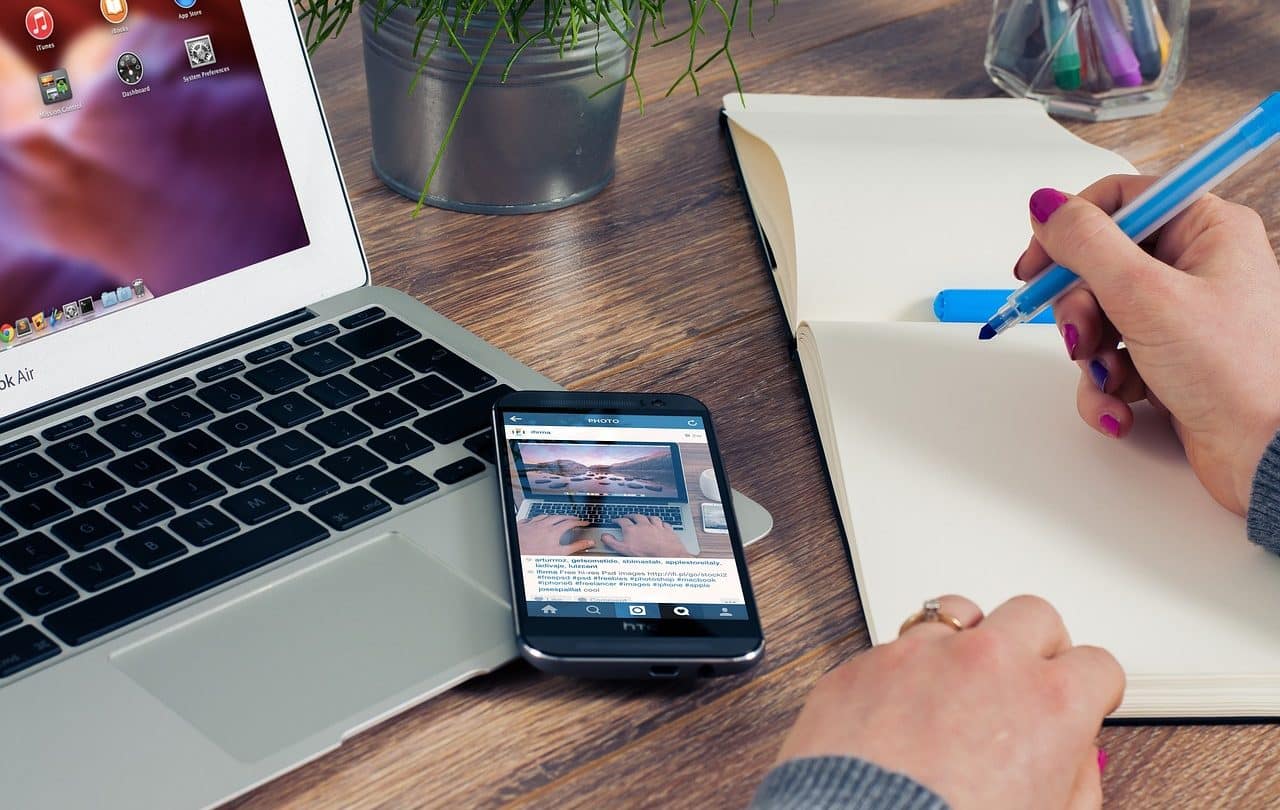 iPhone on laptop and next to notebook.