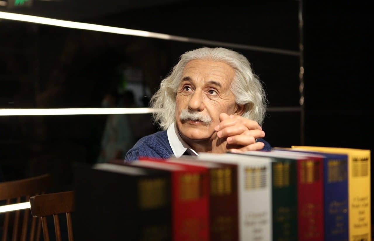 Albert Einstein sitting behind a row of books