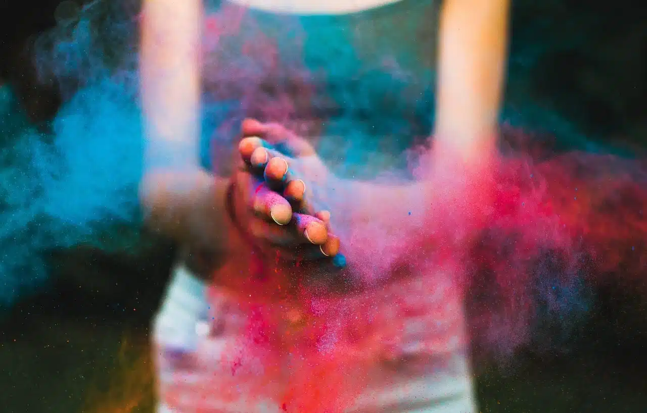 Woman spreading colorful powder in the air