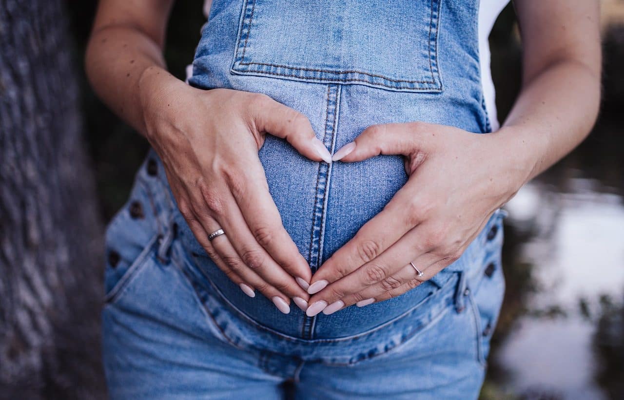 Pregnant woman forming a heart on her belly with her hands