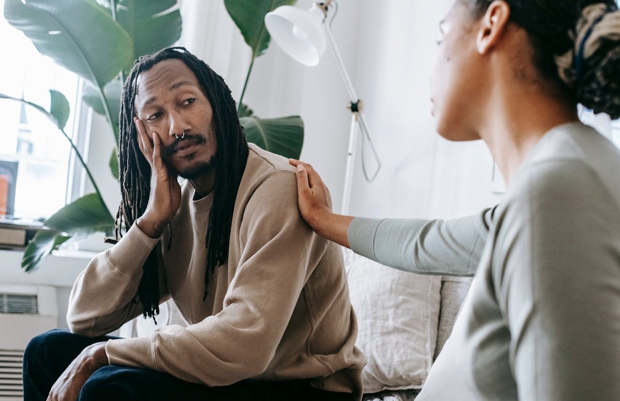 Woman placing her hand on a man&#39;s shoulder, showing him her empathy.