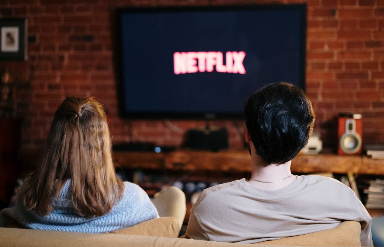 Woman and man sitting on sofa watching Netflix