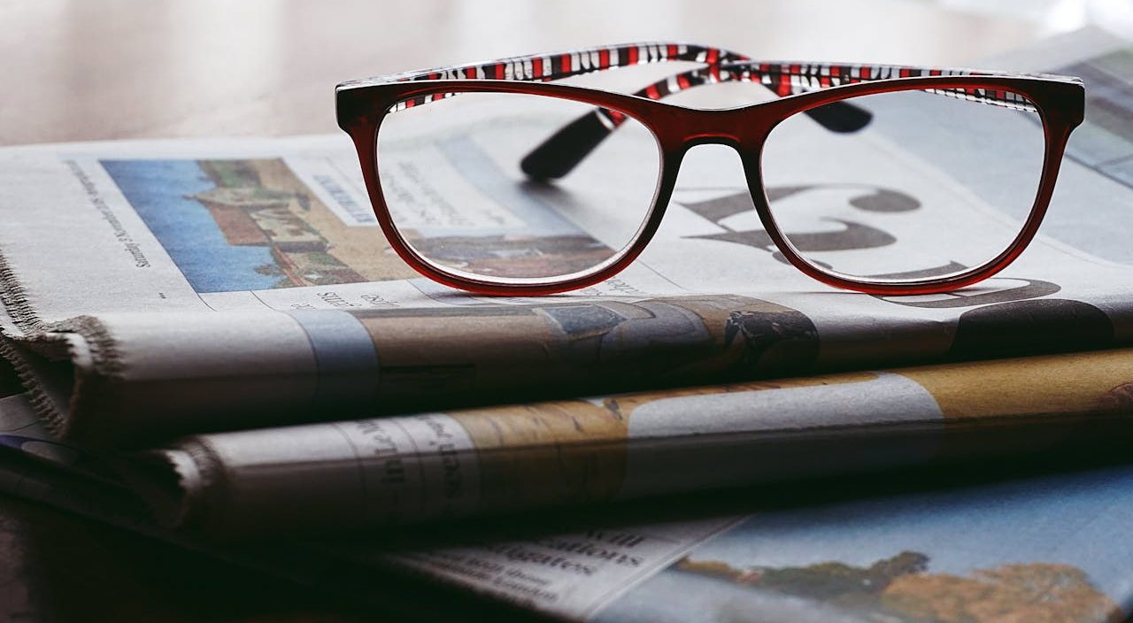 Pile of newspapers with glasses on top