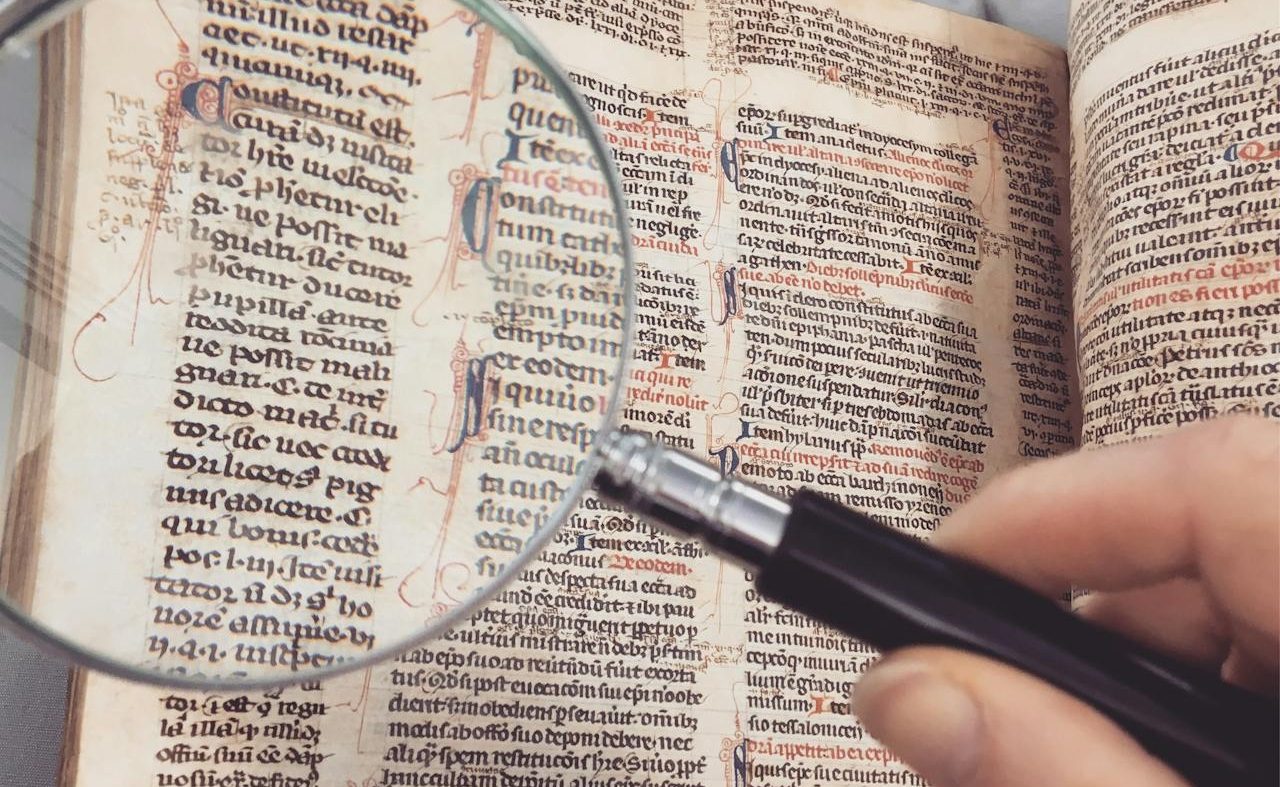 Person reading book with a magnifying glass