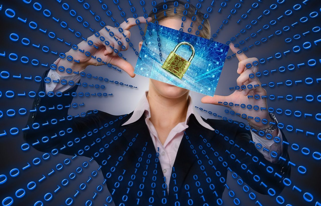 Woman holding a screen on which a golden padlock is seen. Zeros and ones come out from the center in a radial manner.