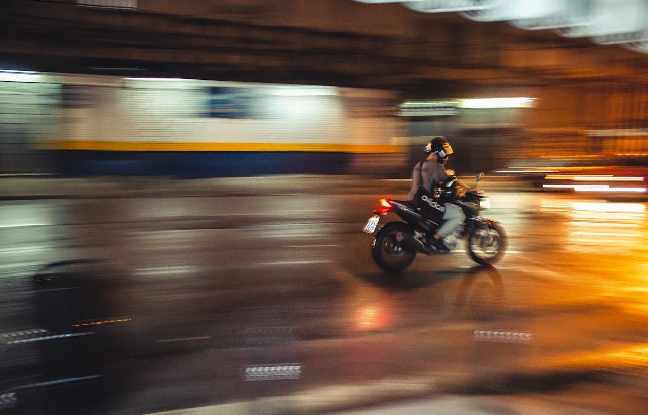 Person traveling on a motorcycle through the city, with the blurred background with speed effect.