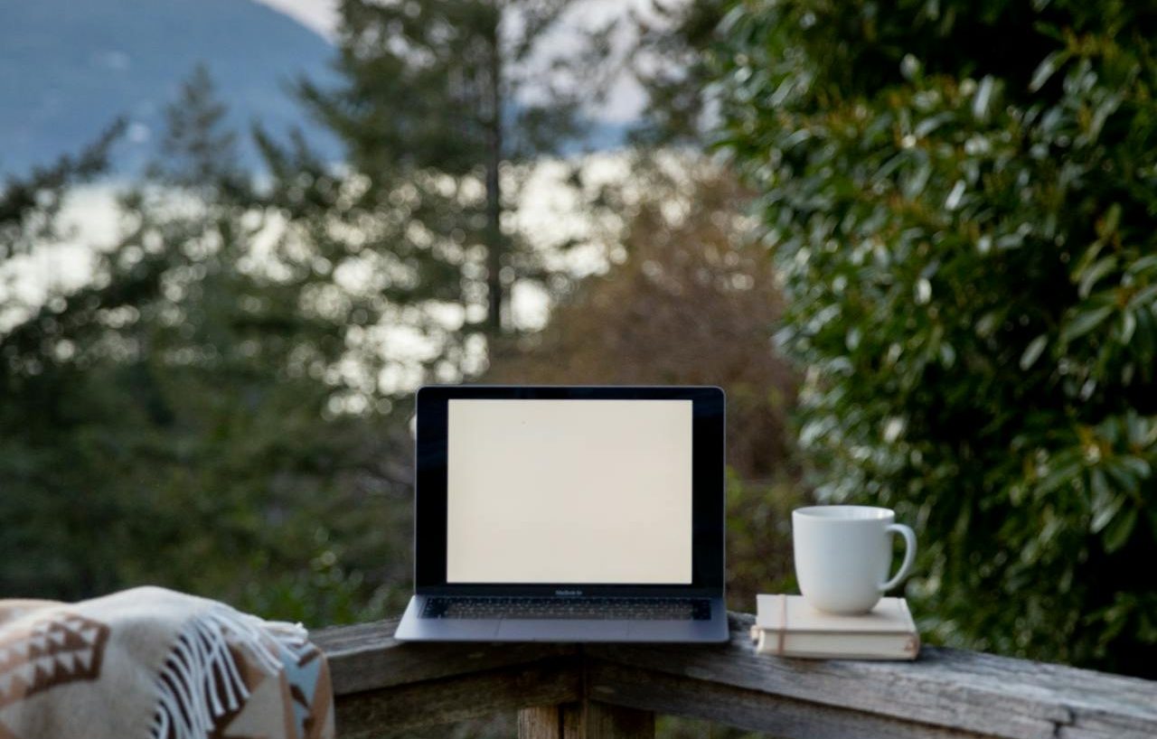 Laptop, cup of coffee and book in a country house