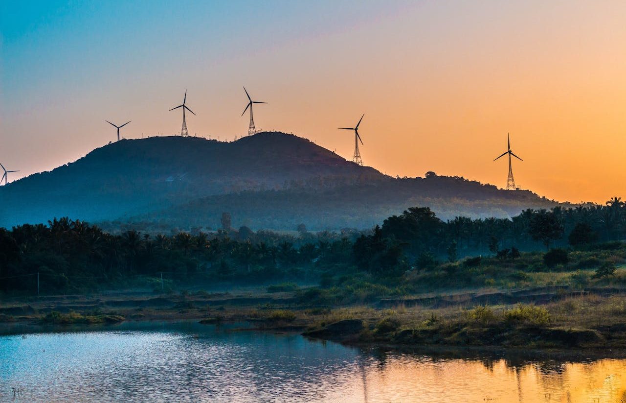 Sunset landscape with wind turbines on hills.