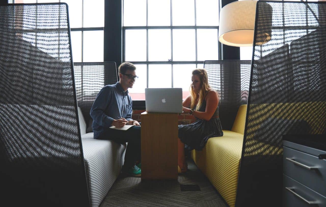 Woman and man chatting while looking at laptop