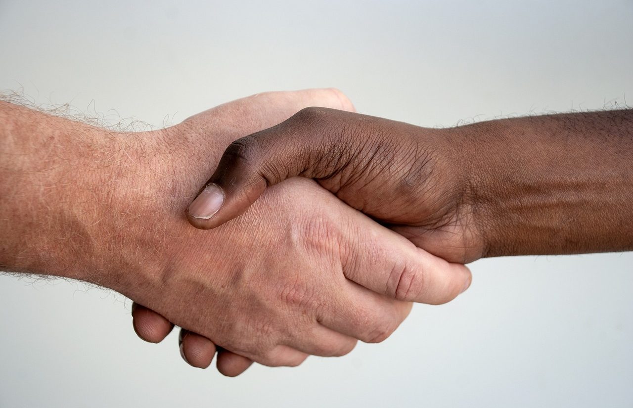 A black man and a white man shaking hands