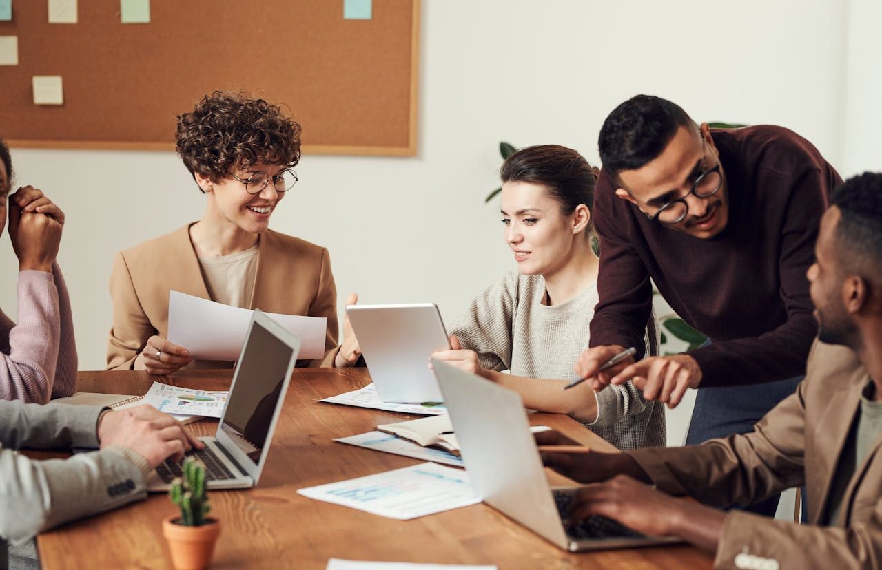 Group of people sitting around an office table with their laptops.