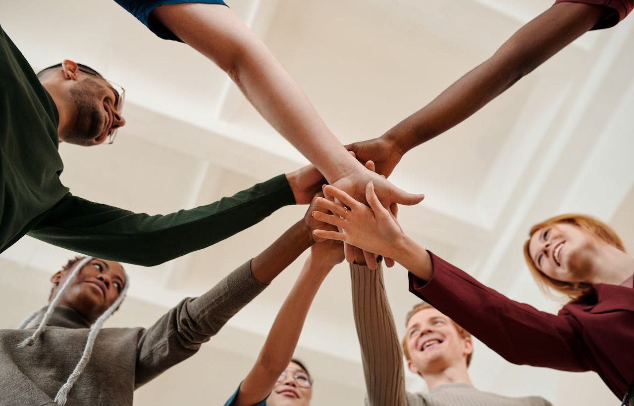 People in a circle joining hands in the center